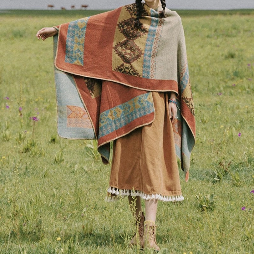 Oversized tribal poncho cloak full body side view showing geometric ethnic print and warm woven fabric in natural pasture setting