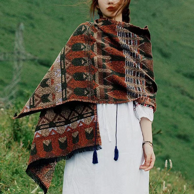 Tibetan pattern scarf wrap with warm earthy tones and geometric tribal designs, worn on alpine grassland with frayed tassel hem