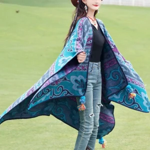 Tibetan ethnic knit wrap with open front design and tassel accents, front three-quarter view on grassland background