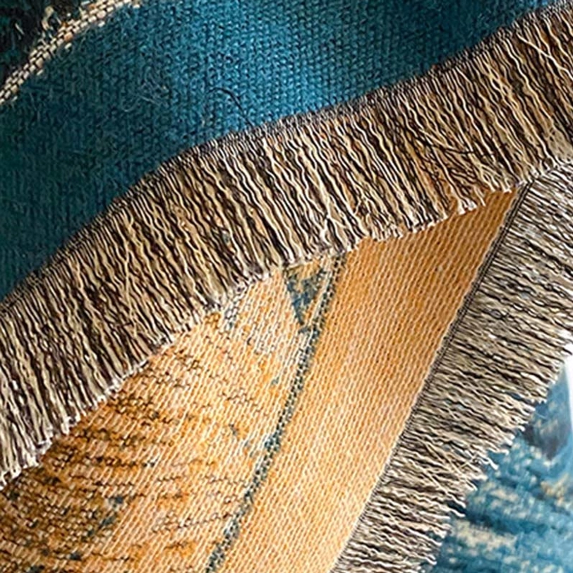 Extreme close-up of Tibetan landscape scarf fabric texture highlighting dense jacquard weave and soft frayed edge detail