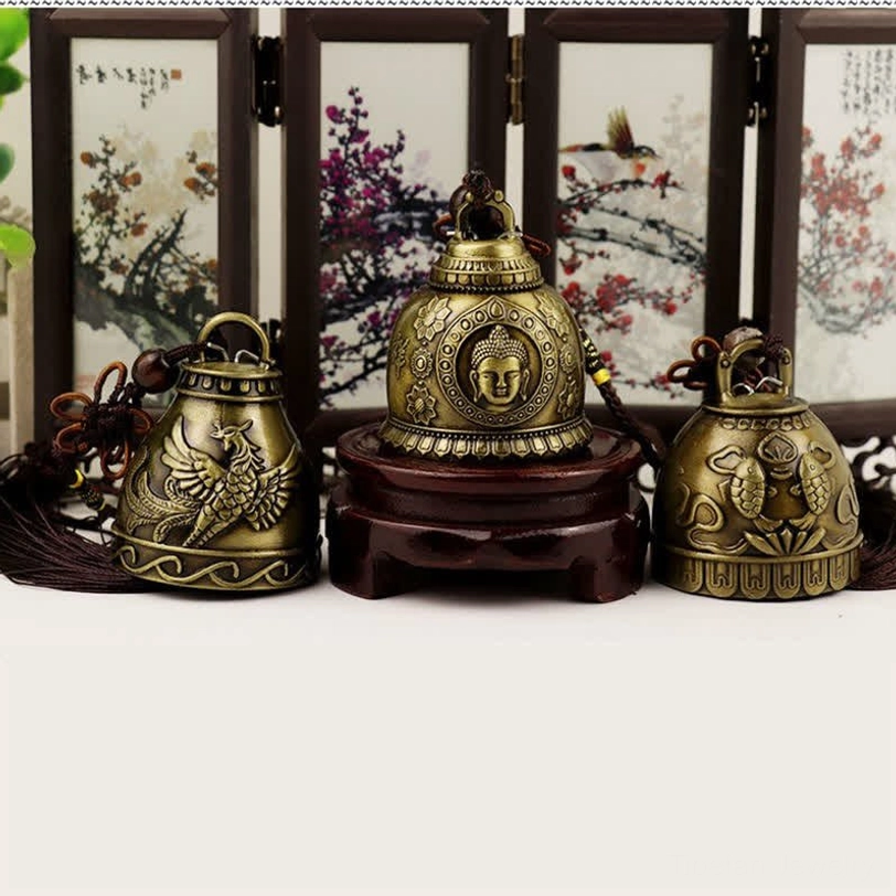Three feng shui wind chimes with Buddha, Phoenix, and Koi Fish designs on wooden stands with folding screen backdrop