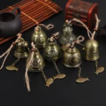 Assorted antique bronze Tibetan feng shui wind chimes with embossed Buddhist patterns displayed with traditional tea set and bamboo accessories