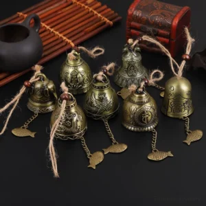 Assorted antique bronze Tibetan feng shui wind chimes with embossed Buddhist patterns displayed with traditional tea set and bamboo accessories