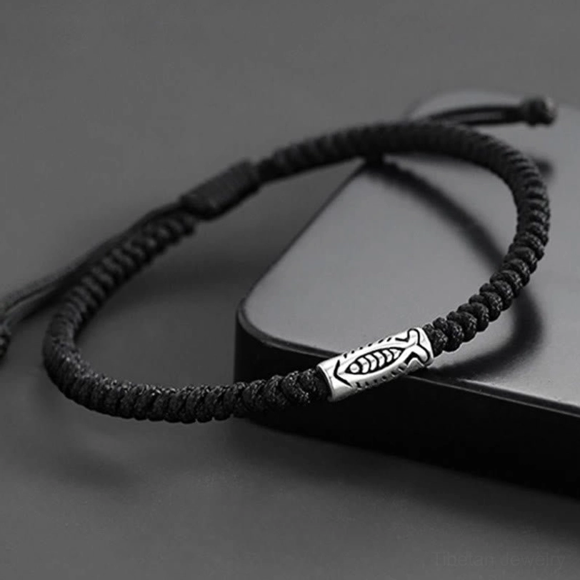 Fish motif black cord bracelet with engraved silver bead and adjustable pull knot on display