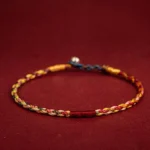 Five-color Tibetan protection bracelet flat lay showing multicolored braided threads with metal clasp on wine red background