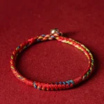Handmade five-color Tibetan protection bracelet with blue, white, red, green, and yellow threads in flat lay view