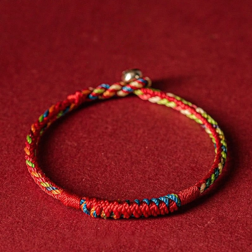 Handmade five-color Tibetan protection bracelet with blue, white, red, green, and yellow threads in flat lay view
