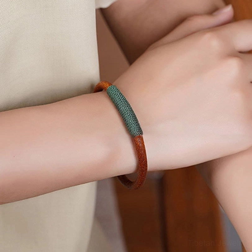 Tibetan five elements leather bracelet with green woven section on forearm - worn lifestyle photo