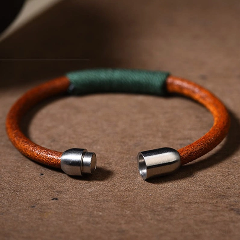 Open Tibetan five elements leather bracelet showing dual magnetic metal clasps and green woven section - front flat lay