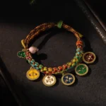 Tibetan five gods of wealth braided bracelet with multicolored rope and enamel metal charms on wooden surface