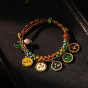 Tibetan five gods of wealth braided bracelet with multicolored rope and enamel metal charms on wooden surface