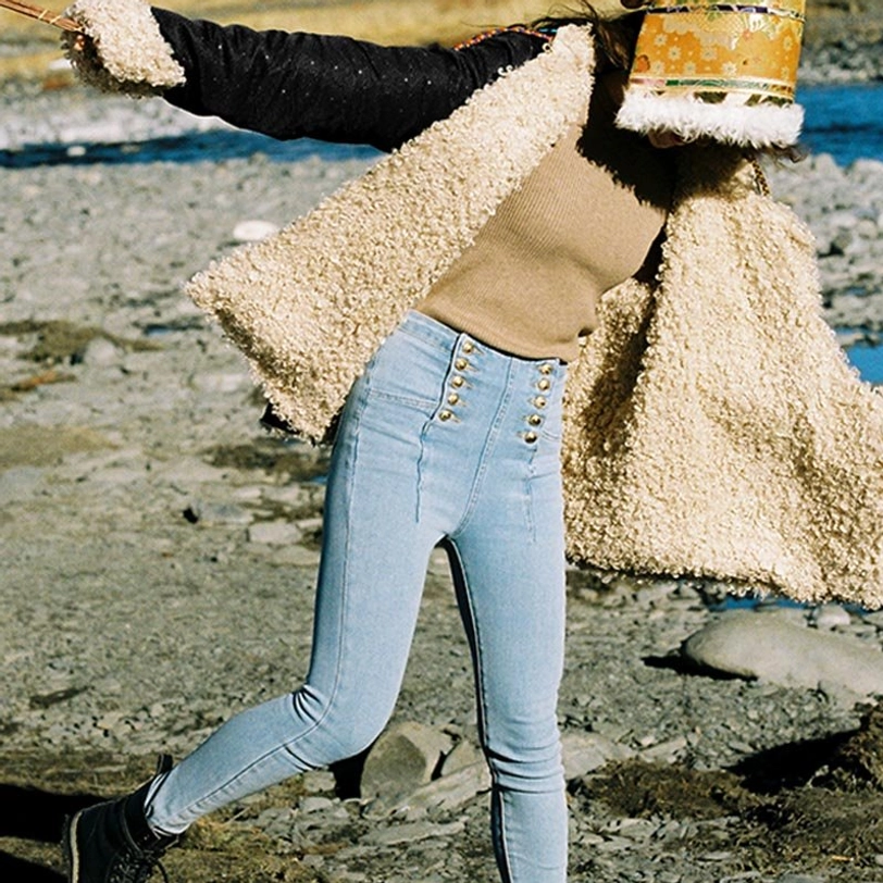 Model wearing Tibetan fleece-lined top unbuttoned outdoors by riverside, showing cozy fleece interior and casual styling with jeans