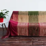 Tibetan handwoven floral chenille throw blanket with geometric ethnic jacquard pattern displayed on sofa, showing burgundy and green tones