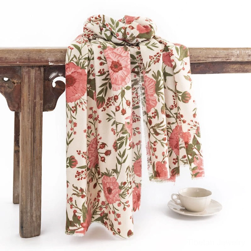 Tibetan floral shawl with pink flowers and green leaves, draped on vintage wooden table, beige soft fabric perfect for fall and winter layering