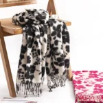 Black tibetan floral tassel shawl draped over wooden chair, showing flower print detail and soft woven fabric