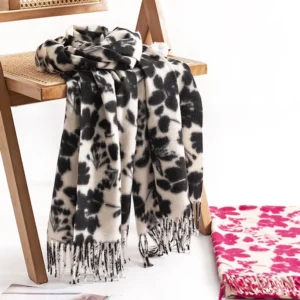 Black tibetan floral tassel shawl draped over wooden chair, showing flower print detail and soft woven fabric