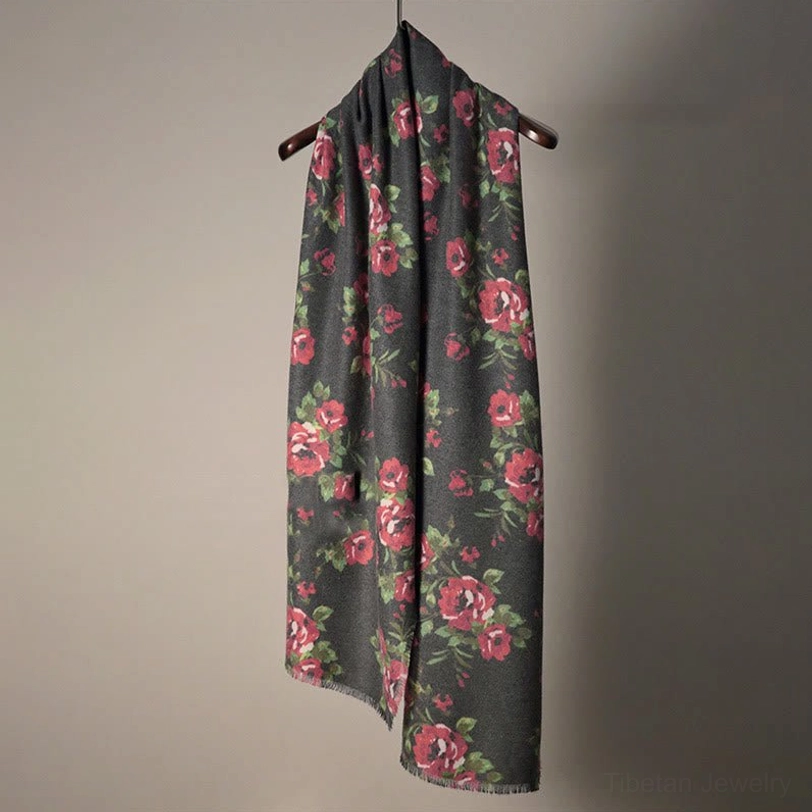 Dark gray Tibetan rose shawl with red roses and green leaf prints hanging on wall background
