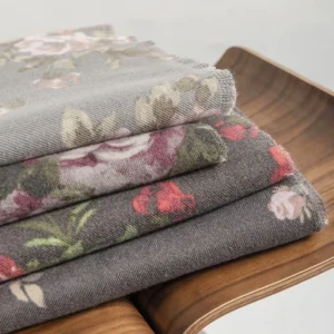 Stack of multiple Tibetan rose floral shawls in muted colors showing layered designs and varied patterns