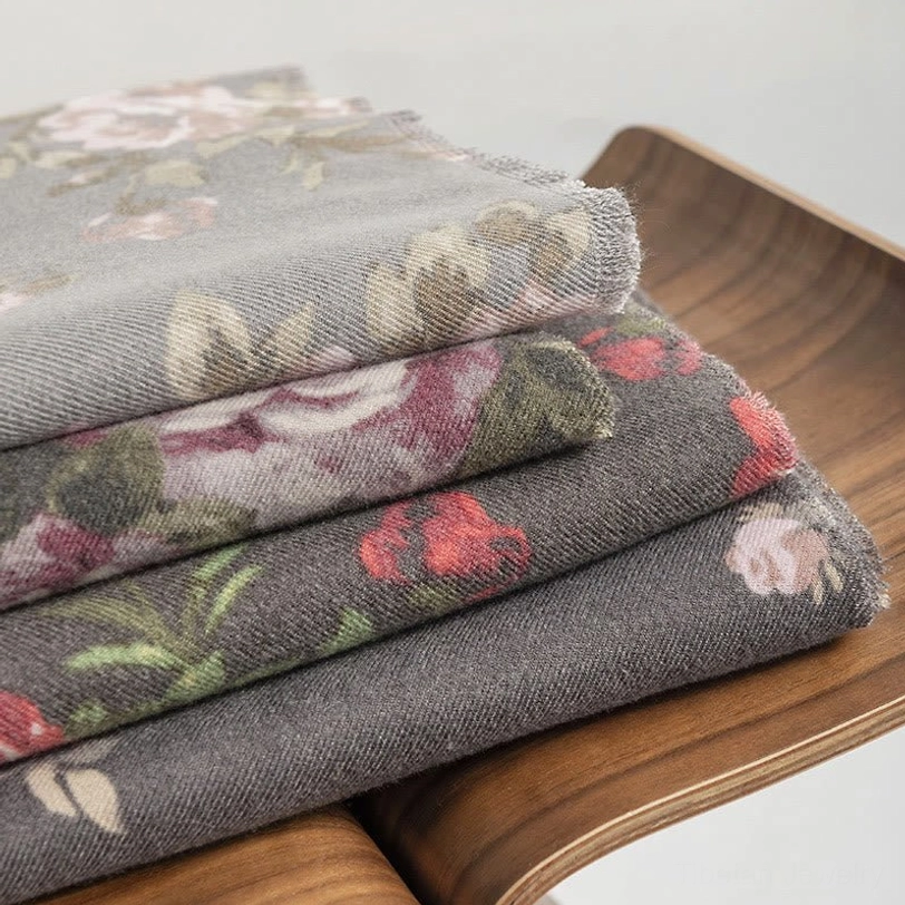 Stack of multiple Tibetan rose floral shawls in muted colors showing layered designs and varied patterns