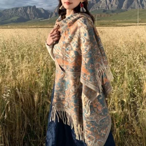 Tibetan floral tassel shawl in beige worn outdoors in wheat field, showing paisley pattern and fringe hem