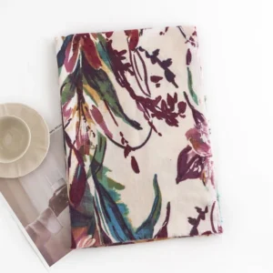Flat lay overhead view of beige Tibetan scarf with watercolor plant print design on neutral background