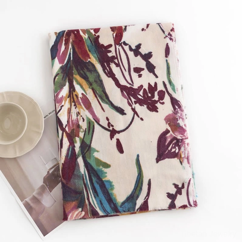 Flat lay overhead view of beige Tibetan scarf with watercolor plant print design on neutral background