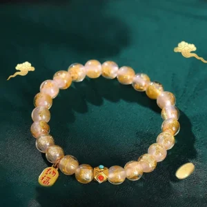 Tibetan incense ash liuli glass fu character bracelet with pink gold foil beads and metal charm on dark green Chinese background