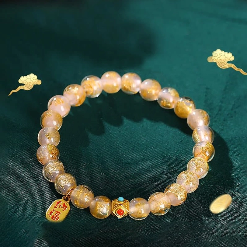 Tibetan incense ash liuli glass fu character bracelet with pink gold foil beads and metal charm on dark green Chinese background