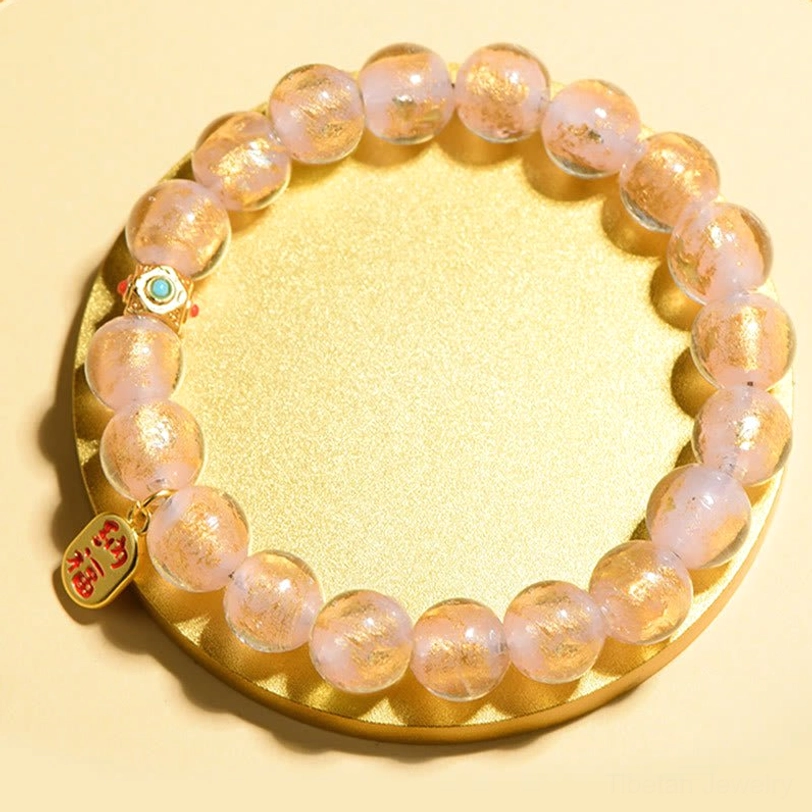 Pink gold foil liuli glass beads fu character bracelet with enamel accents on gold tray display