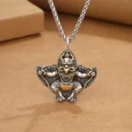 Tibetan Garuda Bird copper protection pendant with wheat chain, two-tone silver and gold finish, detailed carved deity design, overhead view