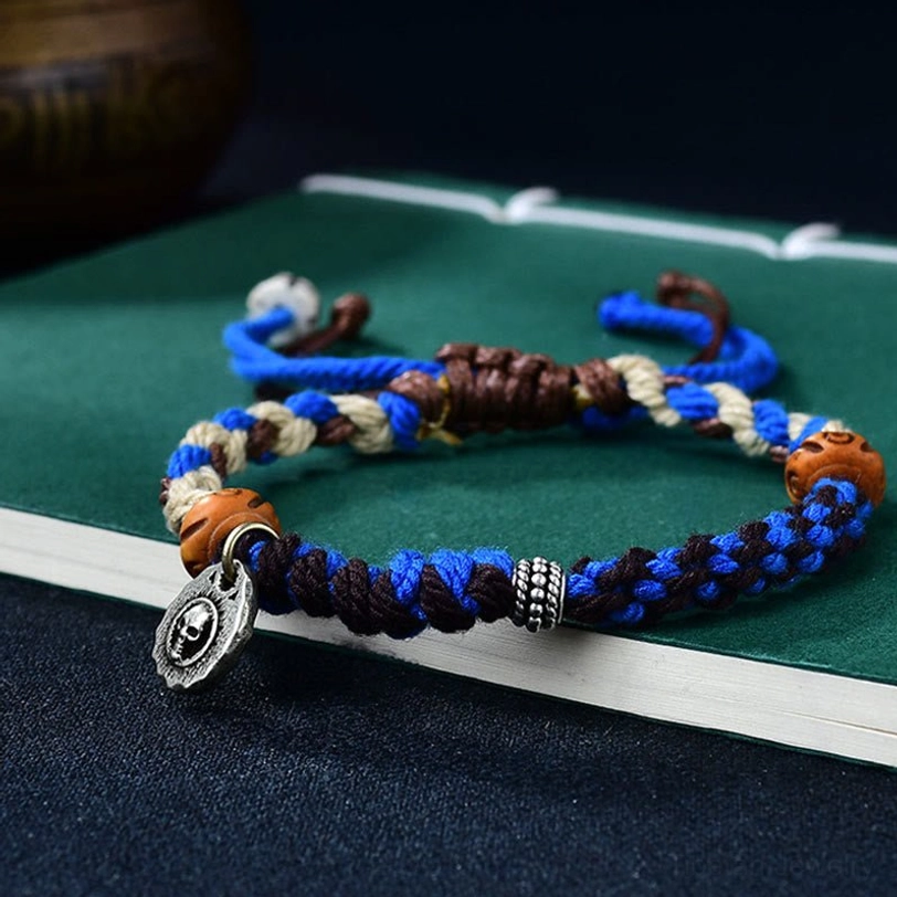 Blue hand-woven Tibetan Garuda bracelet lifestyle view displaying adjustable cord and metal pendant charm