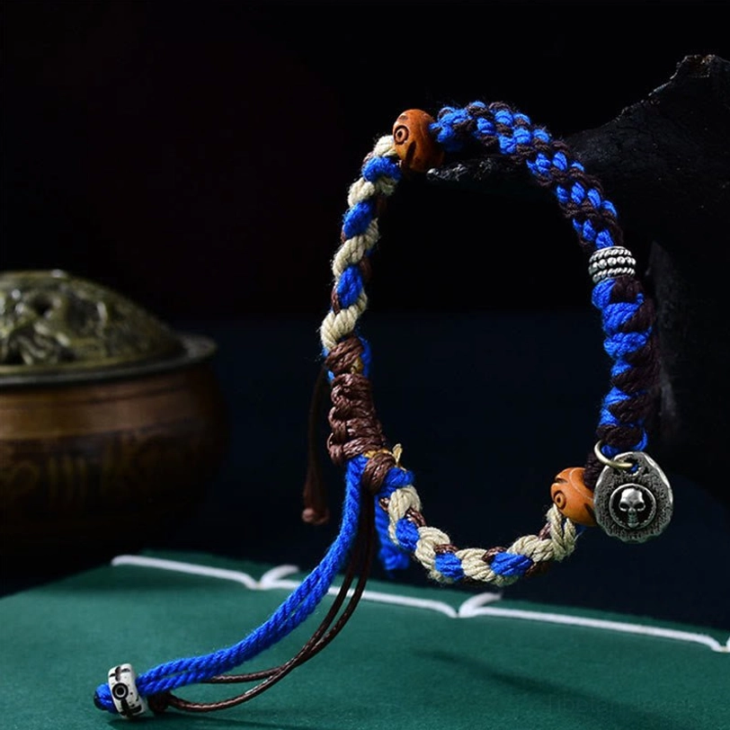 Blue Tibetan Garuda luck bracelet side view showing braided cord, adjustable knots, and engraved charm detail
