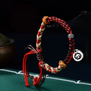 Red Tibetan Garuda luck bracelet side view showing braided cord detail, adjustable knots, and silver charm pendant