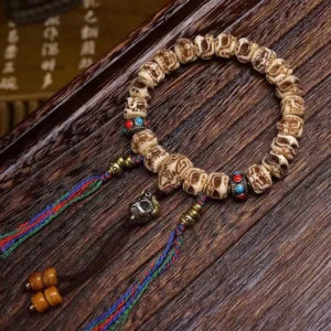 Tibetan camel bone Garuda protection bracelet with carved bone beads, colored agate stones, and vibrant multicolor silk tassel displayed on dark wooden surface