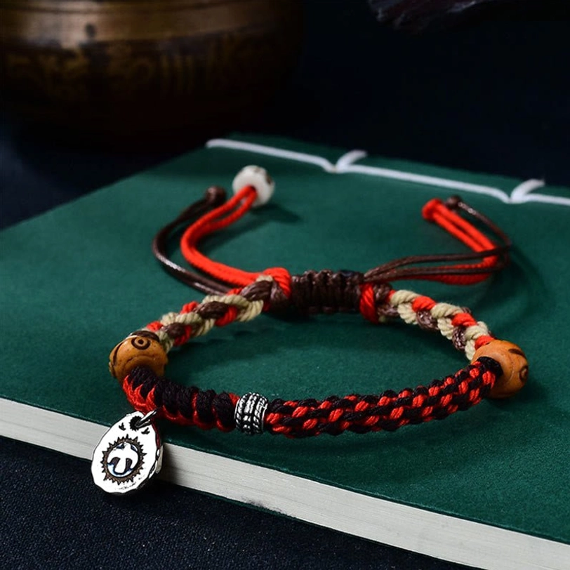 Two matching red Tibetan Garuda protection bracelets with coordinating wooden beads and silver charms displayed together