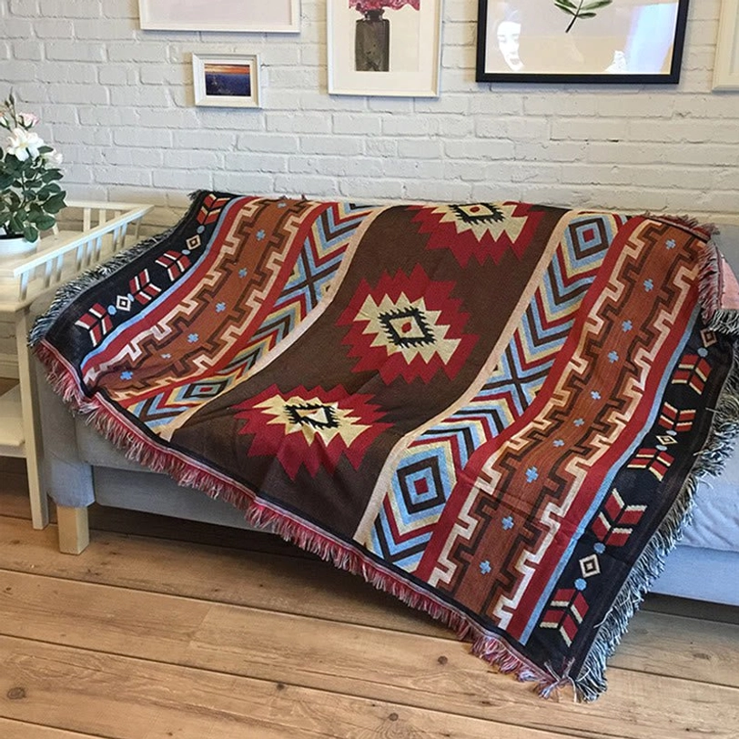 Tibetan geometric hand-woven throw blanket with multi-color tribal patterns displayed on sofa with fringe details