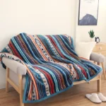 Tibetan geometric throw blanket with bohemian tribal print draped on living room sofa, featuring blue binding edge and multi-color ethnic pattern