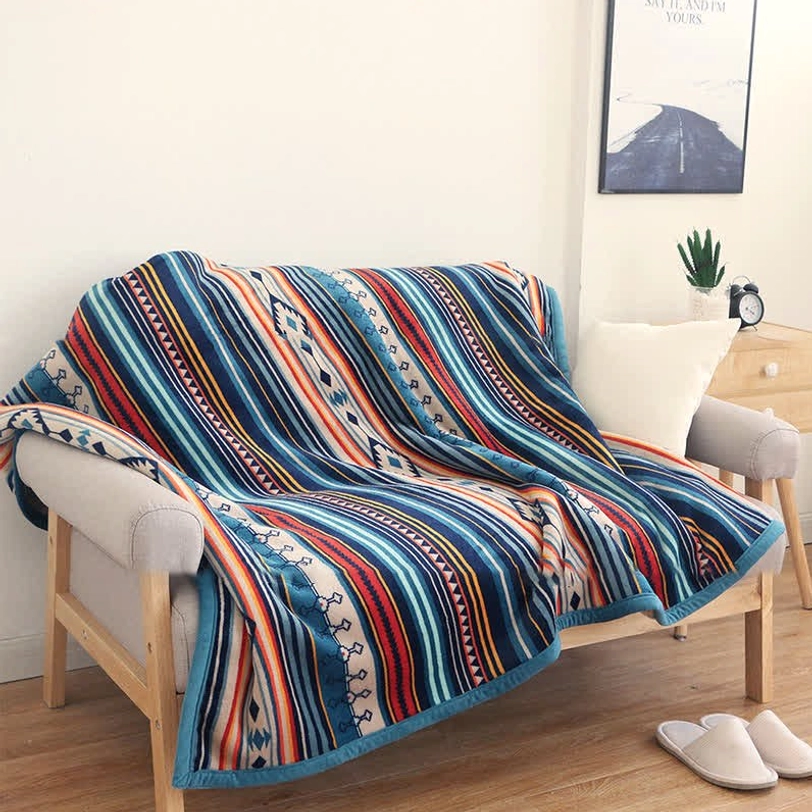 Tibetan geometric throw blanket with bohemian tribal print draped on living room sofa, featuring blue binding edge and multi-color ethnic pattern