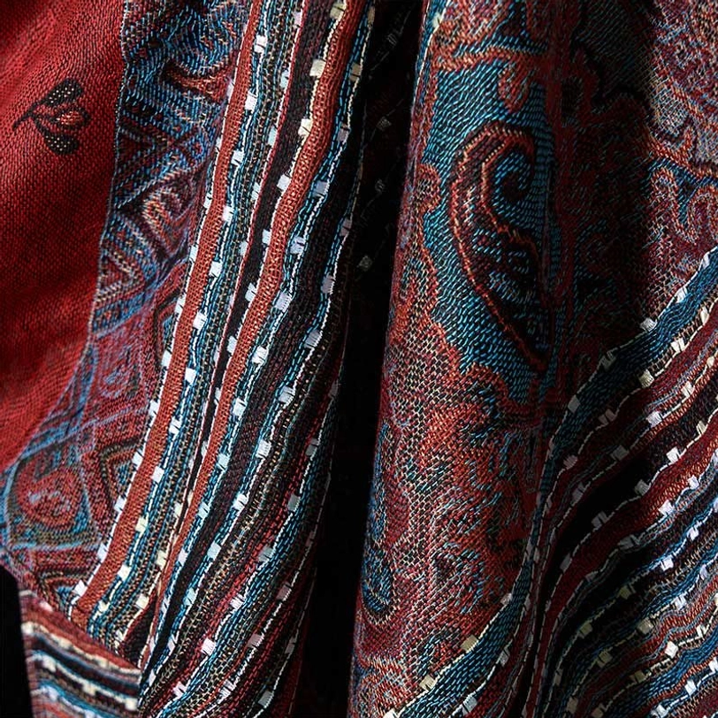 Split close-up view of Tibetan geometric stripe shawl pattern details showing intricate paisley and stripe designs in red and teal color scheme, artisan craftsmanship