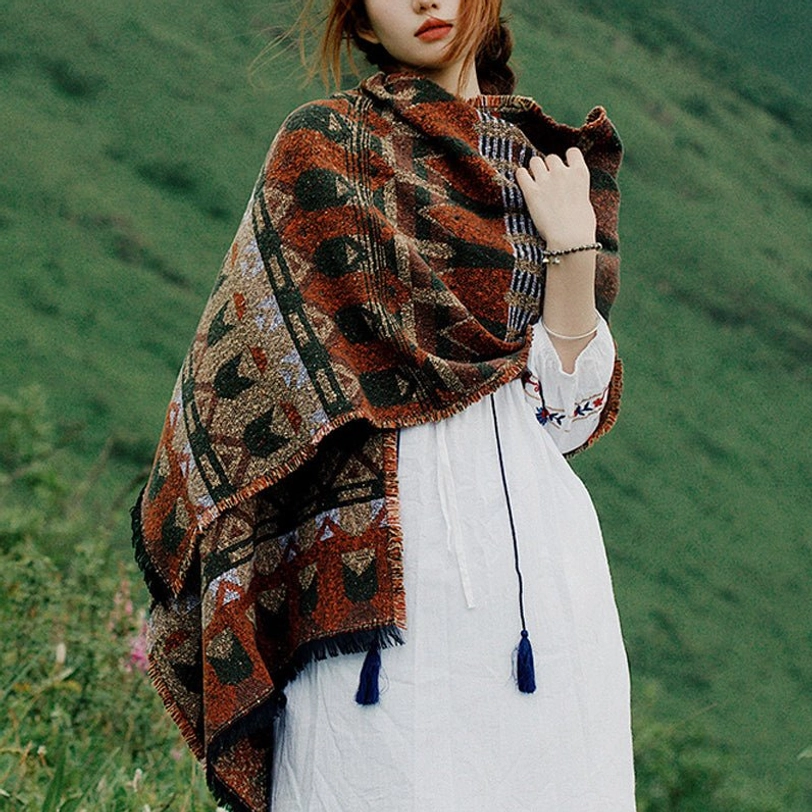 Tibetan geometric tribal woven scarf in rust brown with ethnic patterns and tassel hem, worn outdoors on grassland