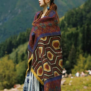 Tibetan geometric shawl worn as outdoor wrap on woman in mountain campsite setting, showcasing brown red yellow and navy blue hexagon pattern with fringed hem