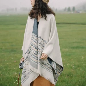 Tibetan geometric tassel shawl with blue beige patterns worn outdoors on grassy field, side view showing fringed tassel hem