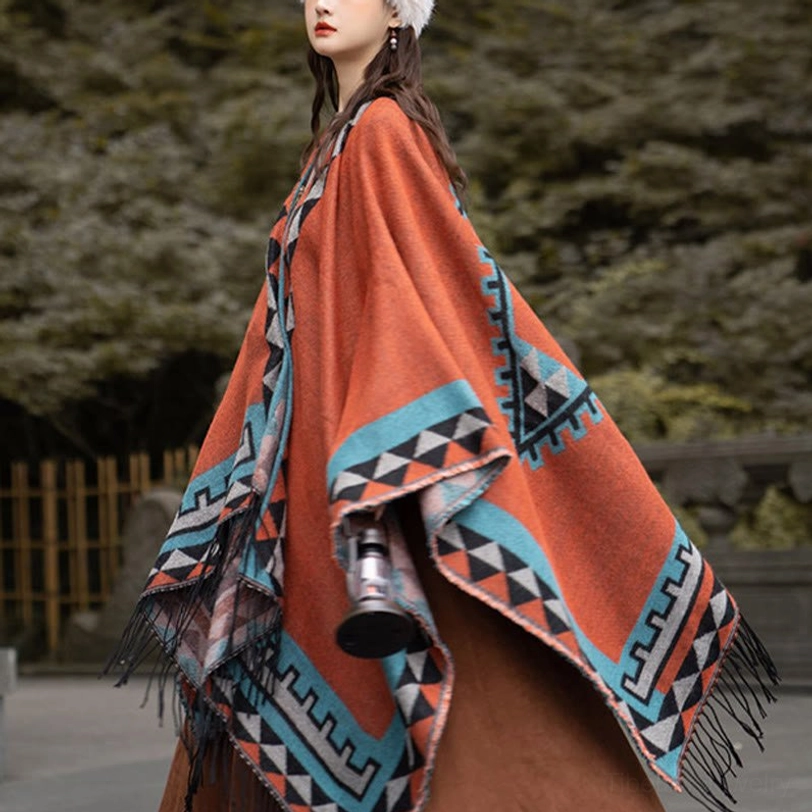 Tibetan orange geometric tassel shawl worn as travel blanket or throw, showing full drape and versatile styling option