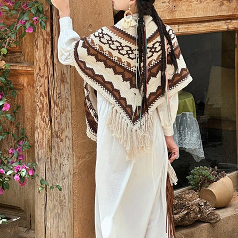 Tibetan geometric knit shawl with flowing tassel hem, side back view against old wooden doorway
