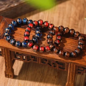 Tibetan style glass beaded bracelets with blue and reddish-brown liuli glazed beads and metallic trim on vintage wooden table background