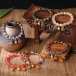 Gold swallowing beast blessing bracelet with liuli glass beads on wooden display stand - overhead view