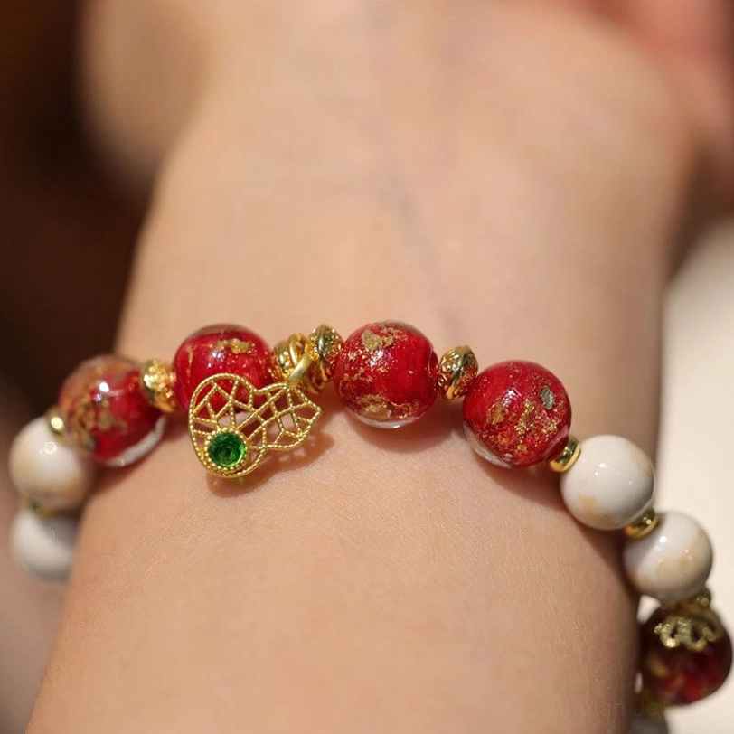Tibetan god of wealth bracelet worn on wrist showing dark red accent bead and traditional elastic cord, close-up wrist wear view