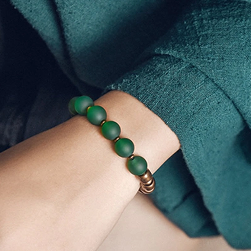Single strand matte green agate bracelet on wrist with antiqued copper spacer beads and elastic fit