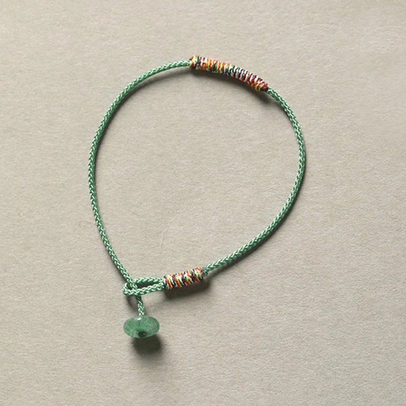 Close-up top view of green aventurine braided Tibetan protection bracelet showing intricate knot detail
