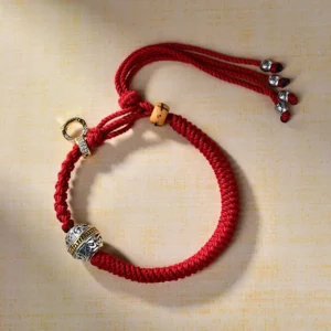 Handcrafted Tibetan Green Tara bracelet side view showing carved silver pendant, red braided cord, wooden accents, and adjustable crystal tassel